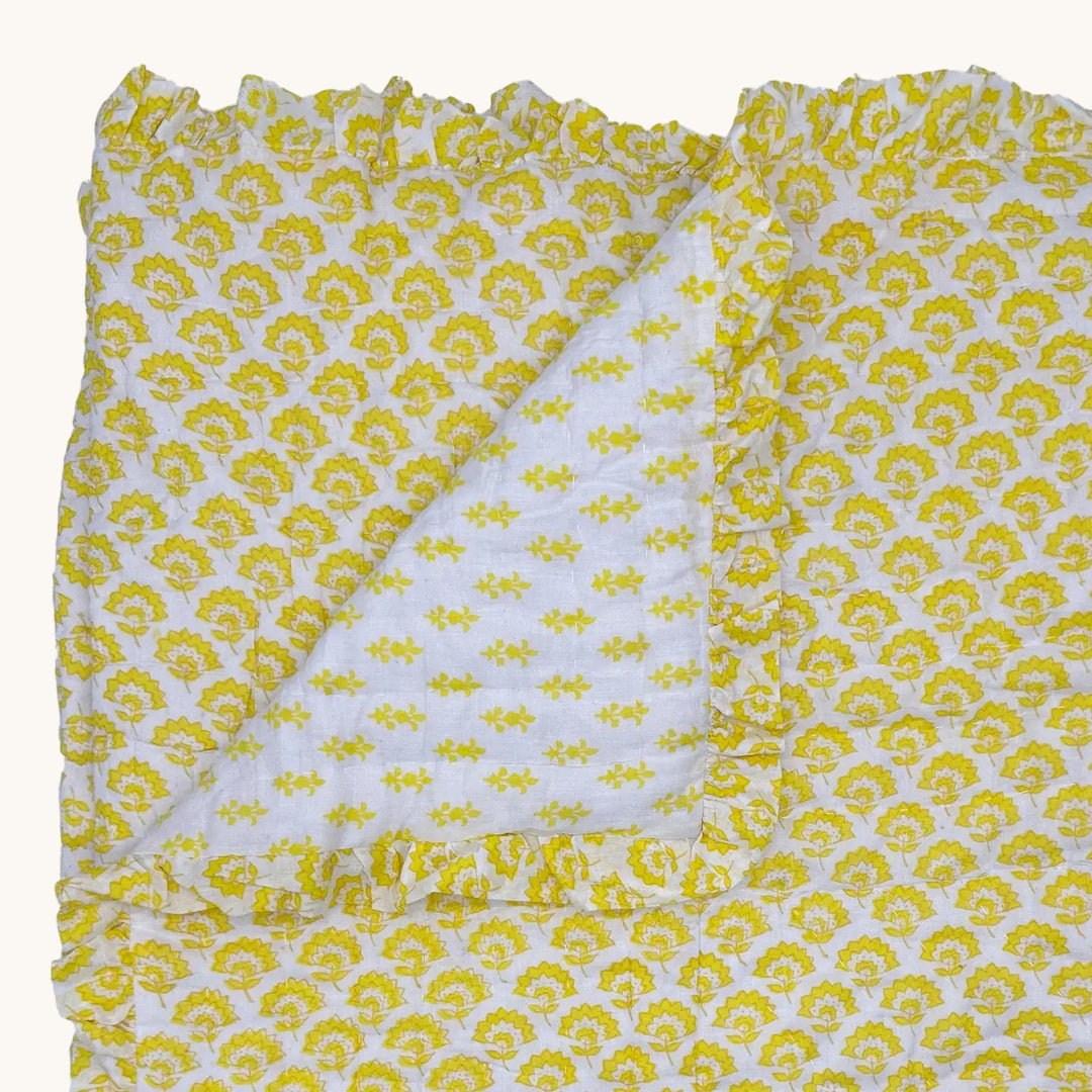 Yellow and white handblock printed quilted cotton throw blanket featuring a reversible floral pattern