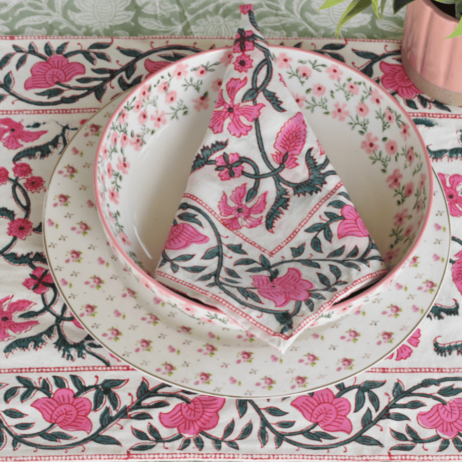 Floral table setting with plates and napkin on a matching tablecloth.