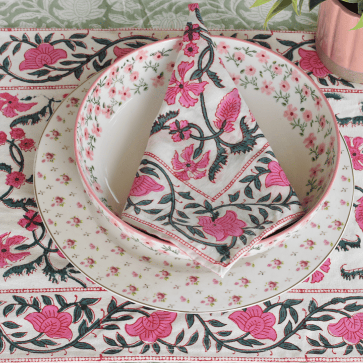 Floral table setting with plates and napkin on a matching tablecloth.