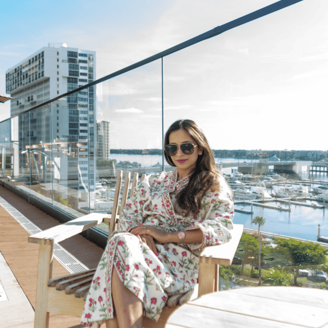 Woman sitting on a balcony wearing robe with a cityscape and marina view