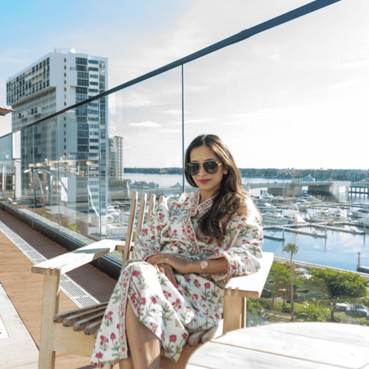 Woman sitting on a balcony wearing robe with a cityscape and marina view