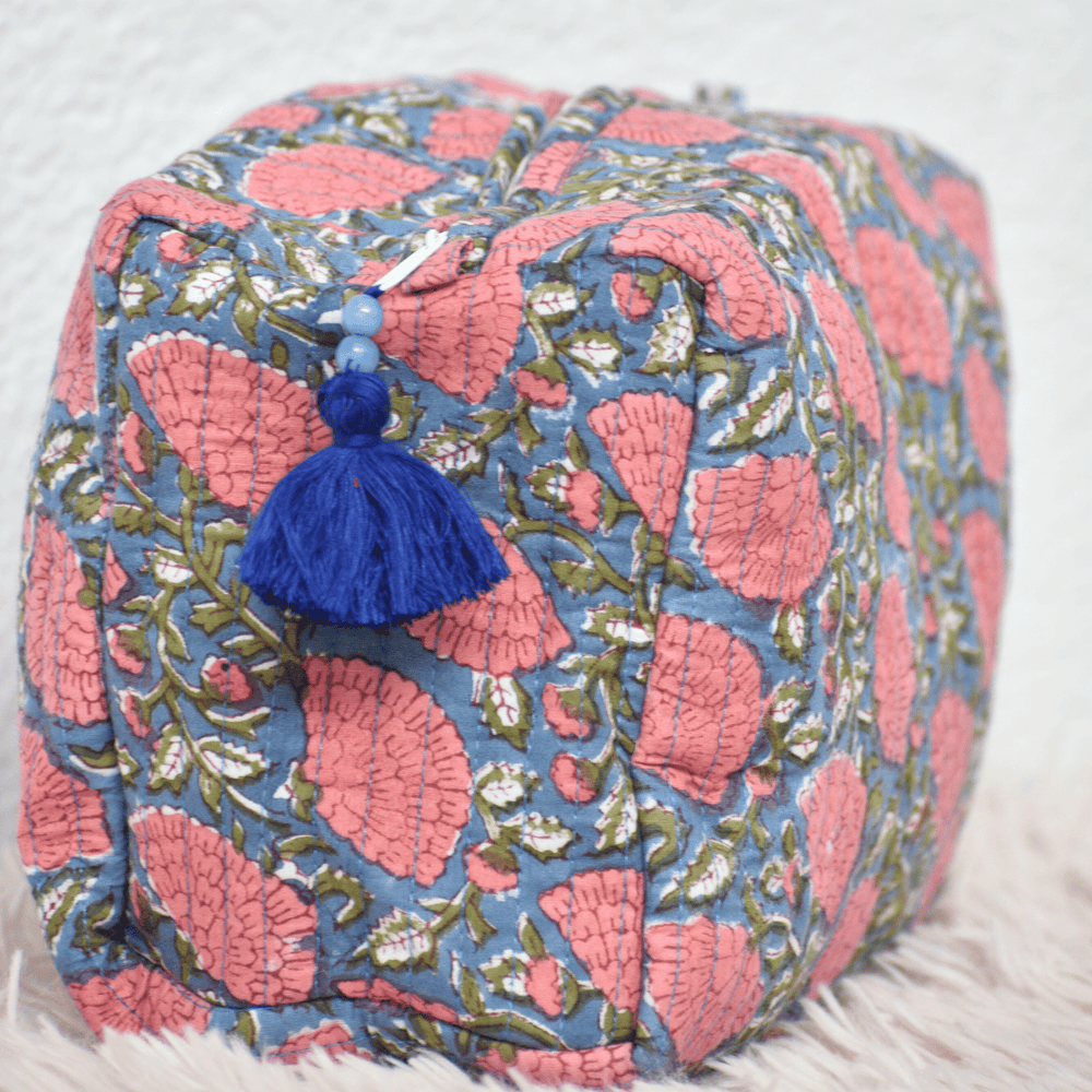 Decorative pouch with pink and blue floral pattern and tassel on a light background
