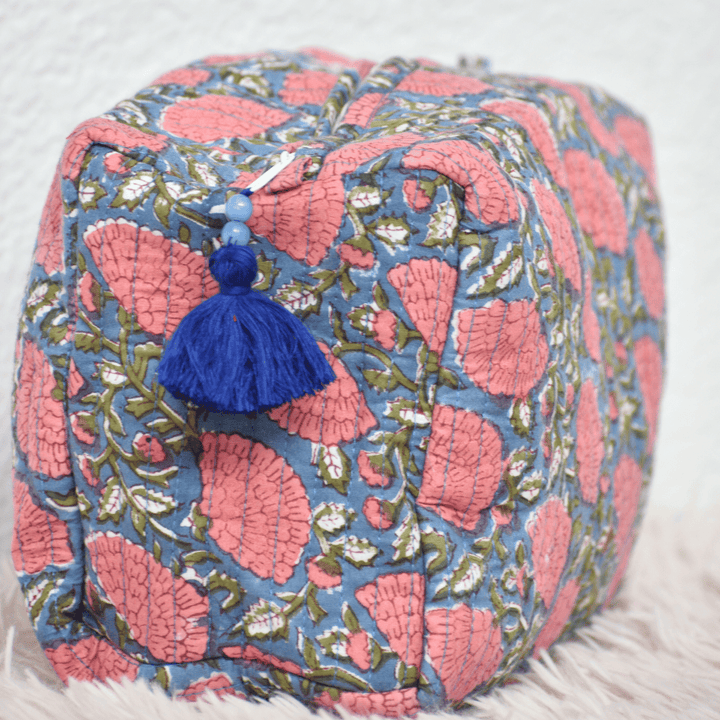 Decorative pouch with pink and blue floral pattern and tassel on a light background