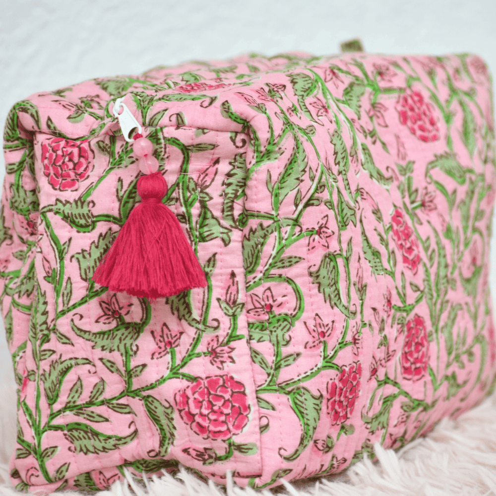 Pink and green floral patterned pouch with a pink tassel on a white background