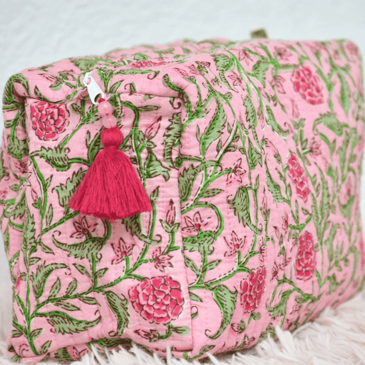 Pink and green floral patterned pouch with a pink tassel on a white background
