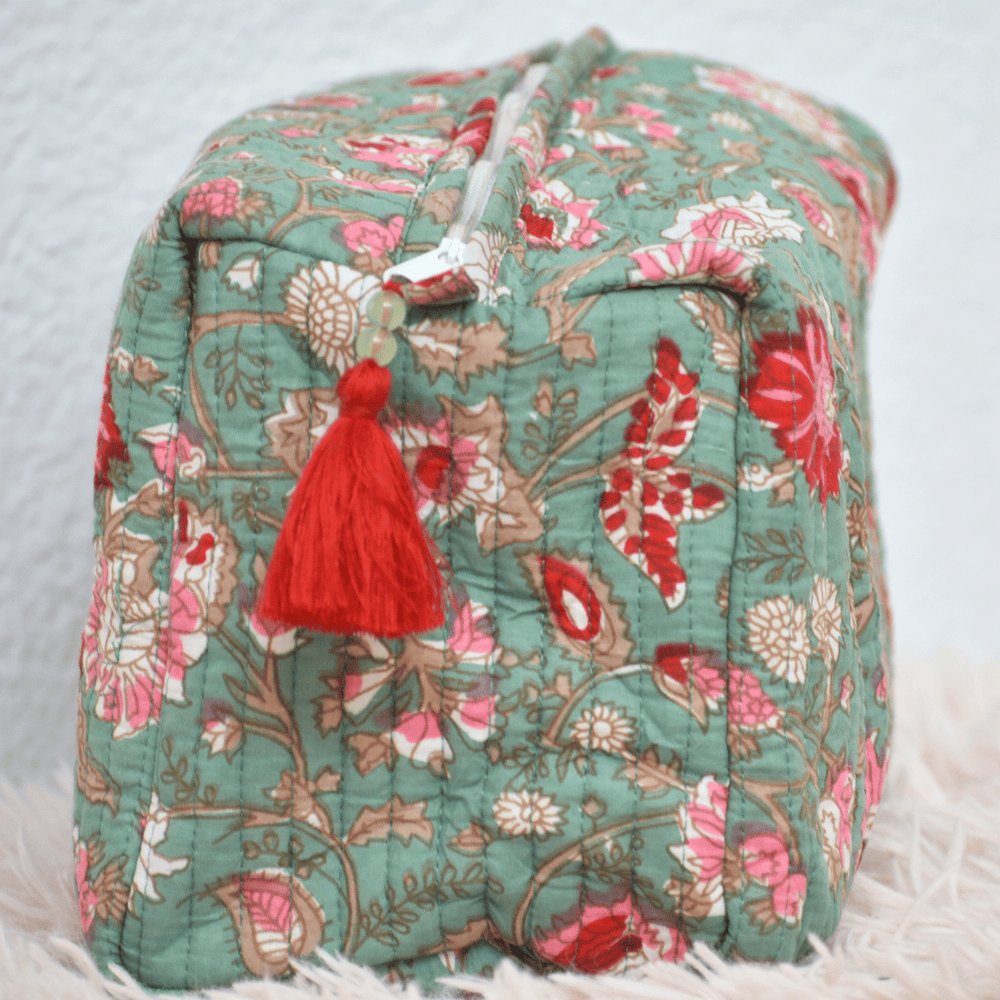 Floral-patterned pouch cube with a red tassel on a light background