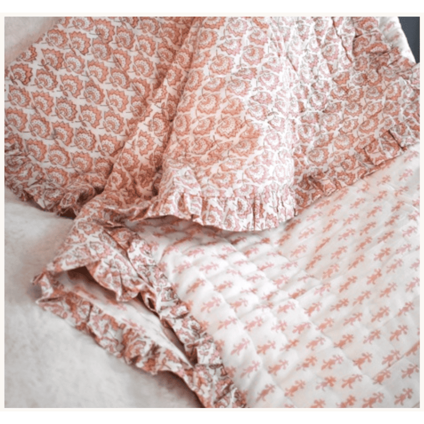Handblock printed quilted throw blanket casually layered on a bed